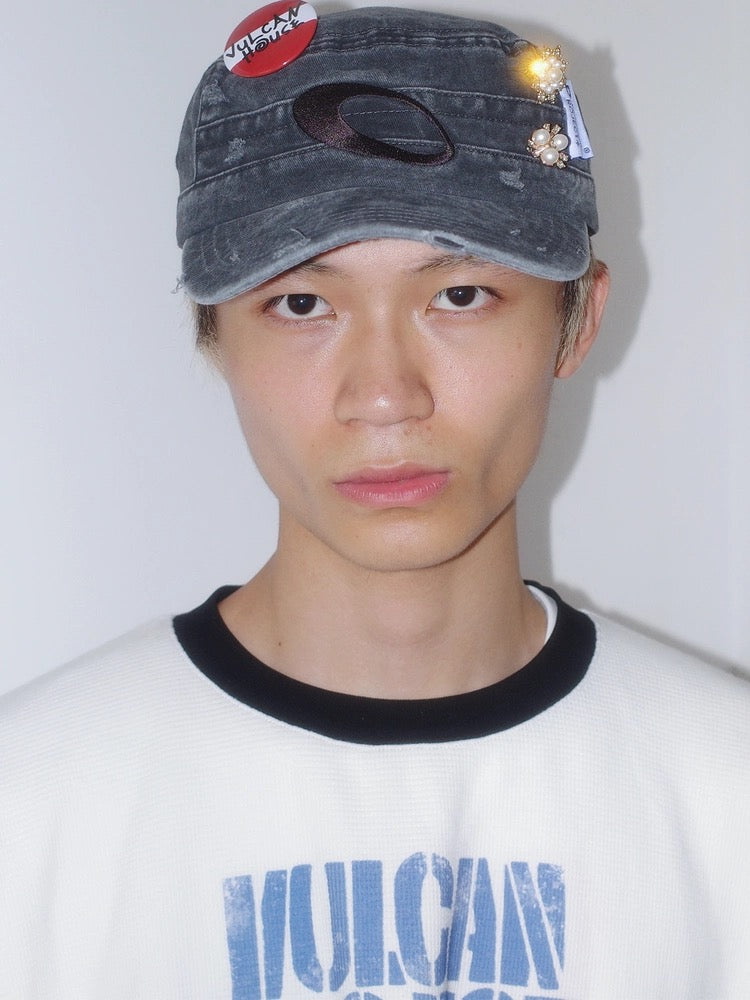 Person wearing a cap with decorative elements on a plain background