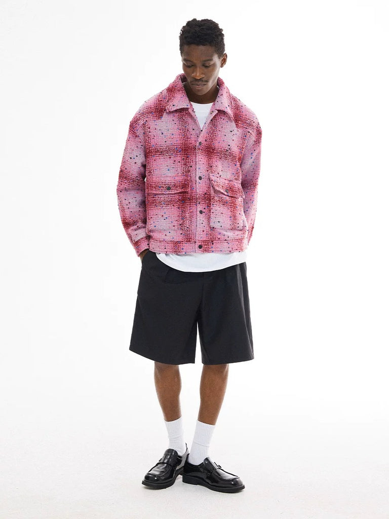 Person wearing a pink plaid jacket, white shirt, black shorts, and black shoes on a white background